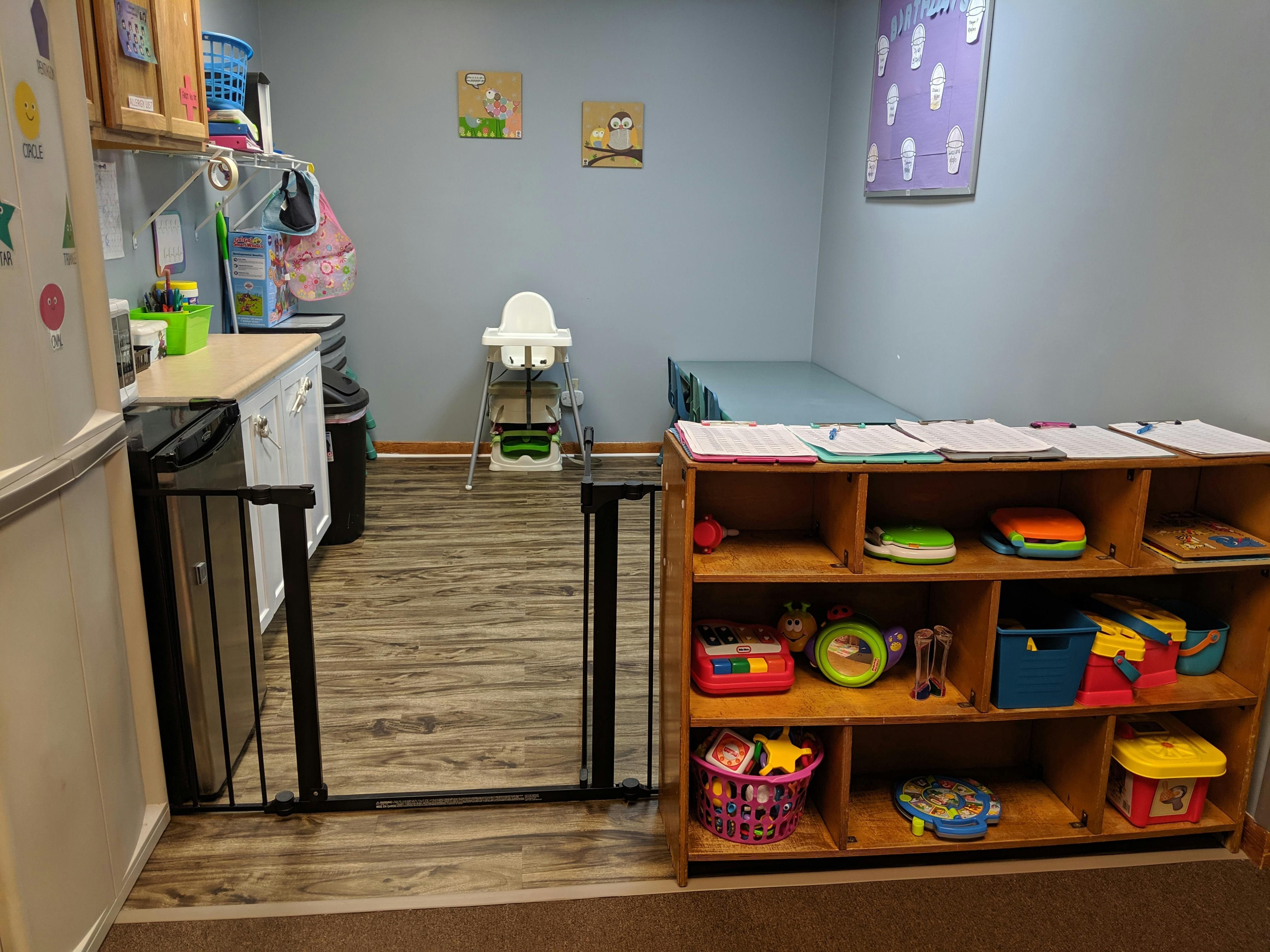 Child safety gate in a room with a high chair and toy shelf