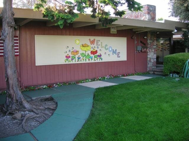 Building exterior with a "WELCOME" sign and colorful flowers