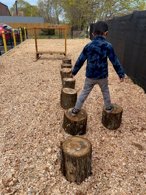 Child balancing on tree stumps in a playground