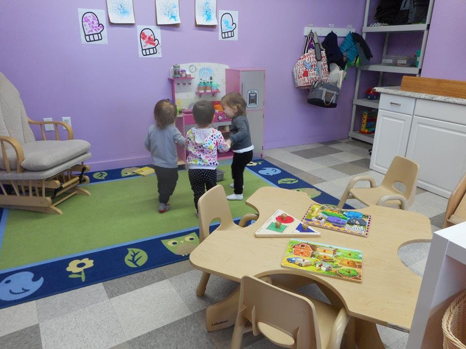 Three children standing on a rug in a classroom