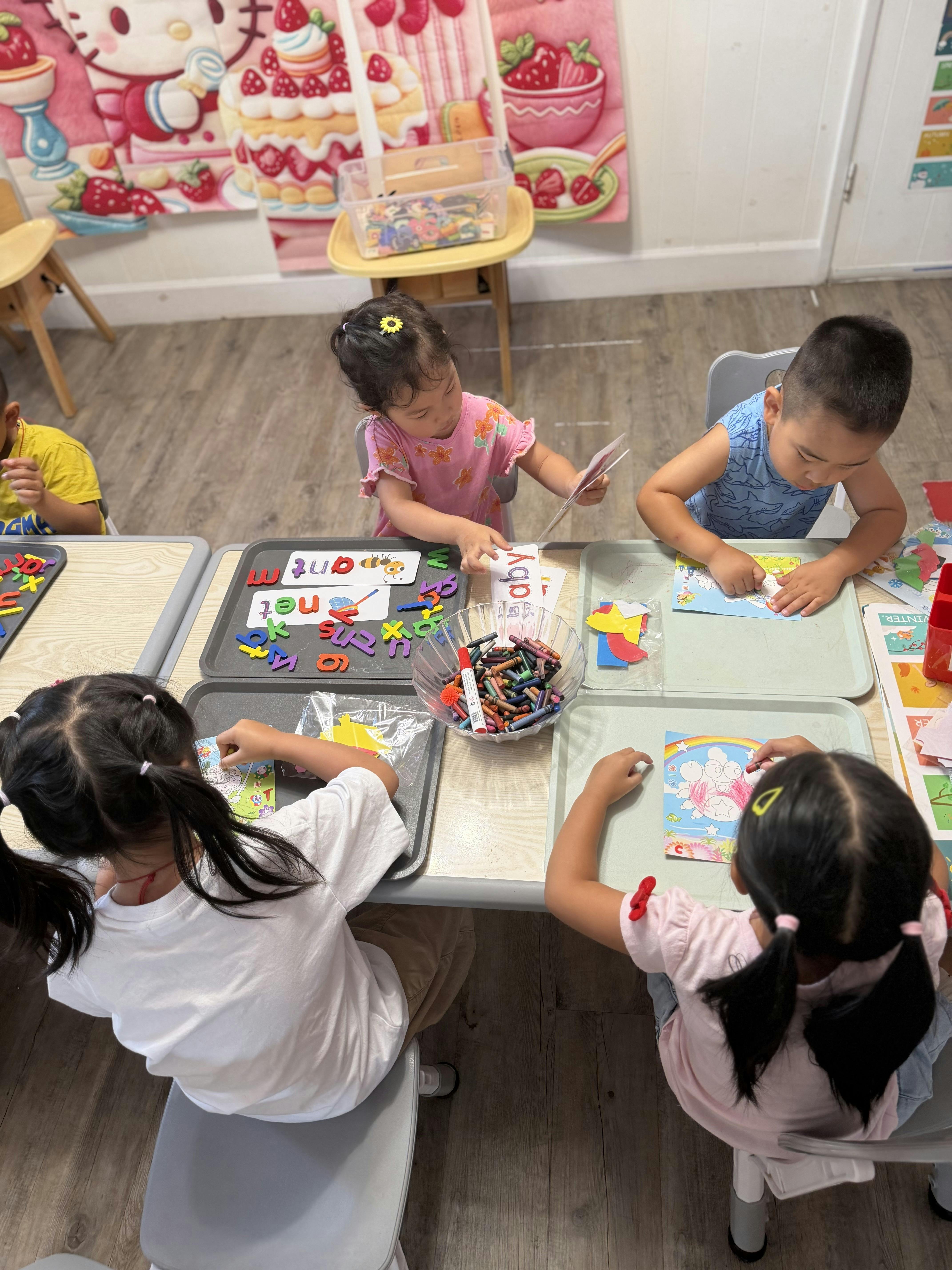 Children sitting at tables engaged in arts and crafts and word activities