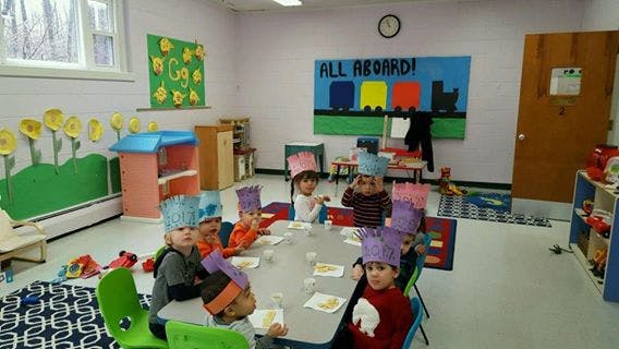 Children wearing paper crowns sitting at a table in a classroom