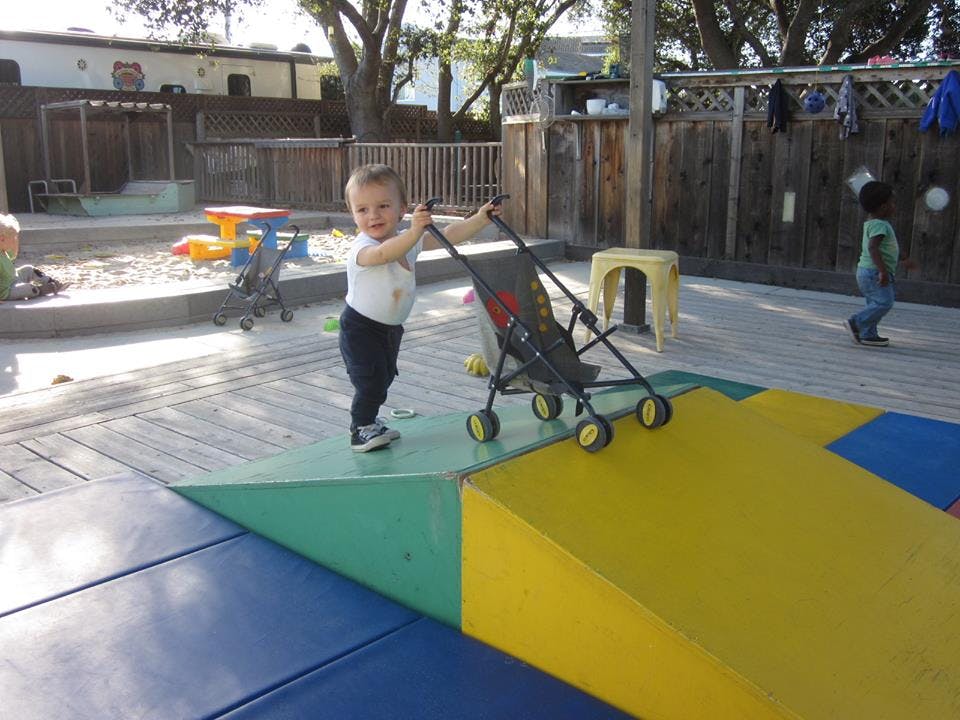 Child pushing a toy stroller on a playground