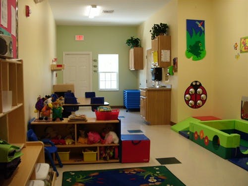 Playroom with toys, shelves, tables, and a soft play area