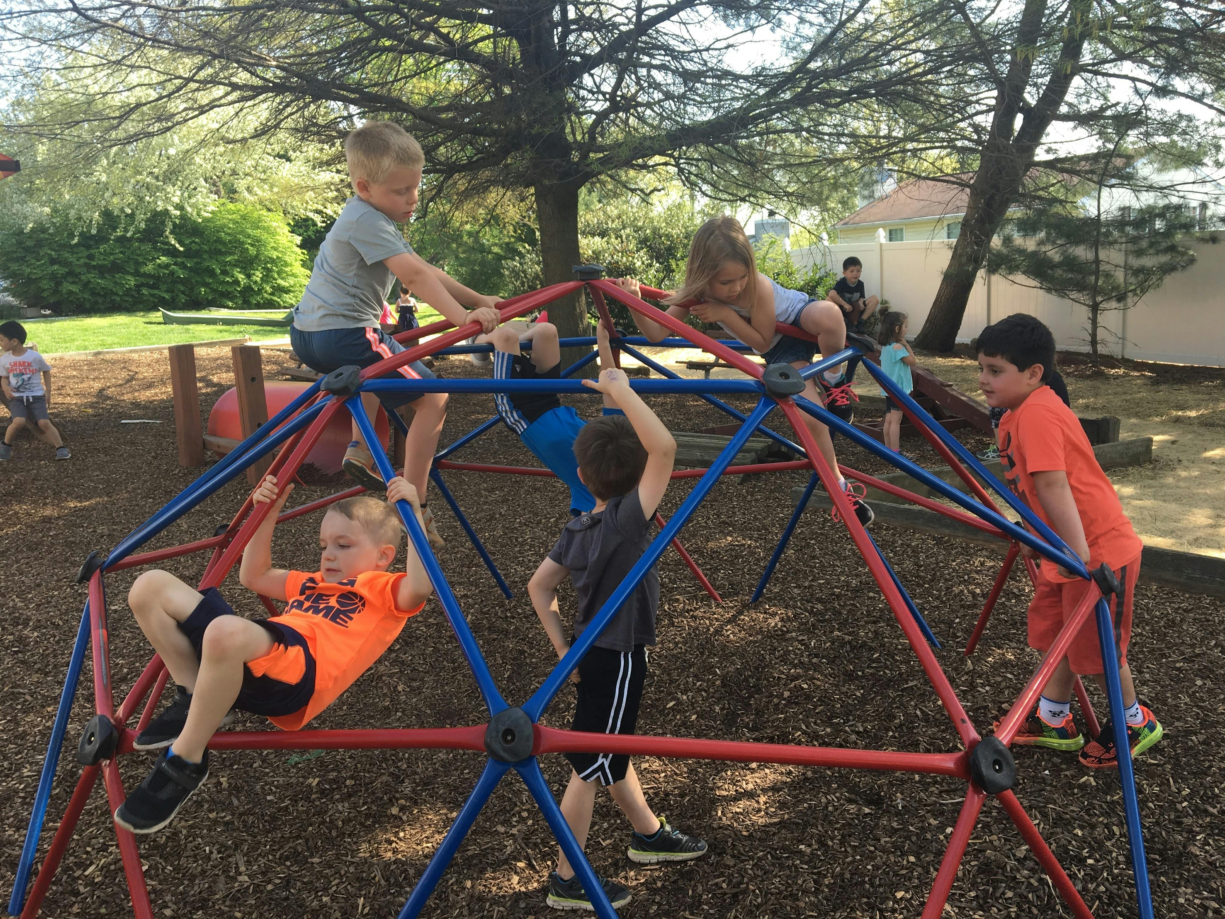 Children climbing on a red and blue dome-shaped playground structure