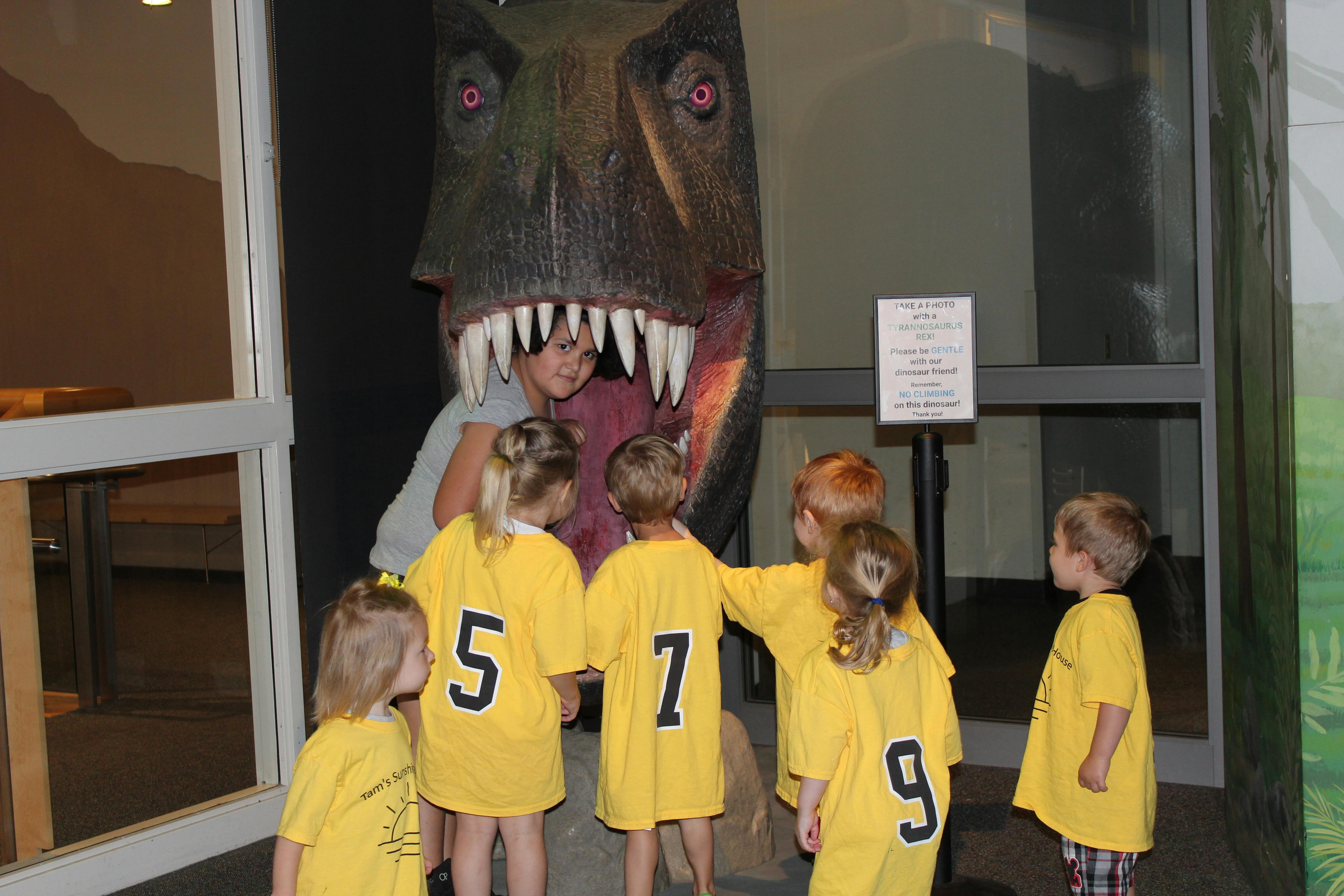 Adult and children looking at a dinosaur head display
