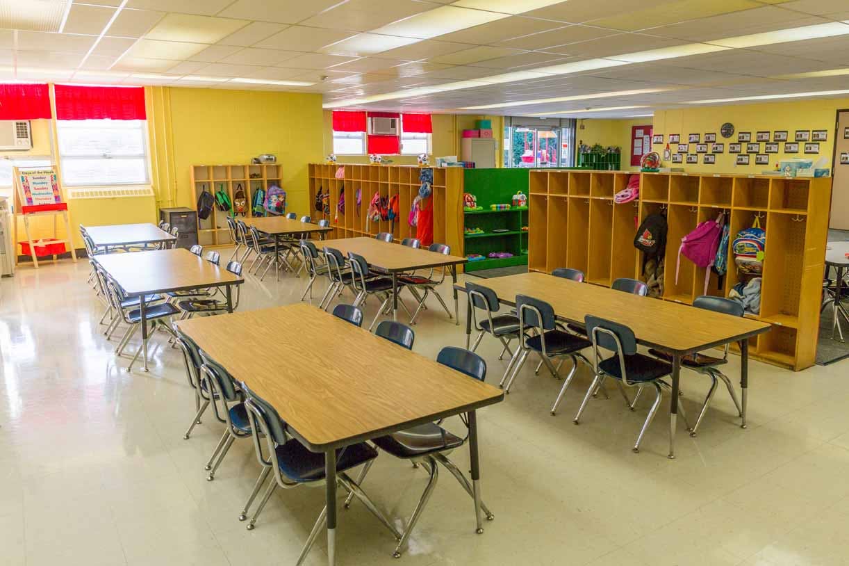 Empty classroom with tables, chairs, and cubbies