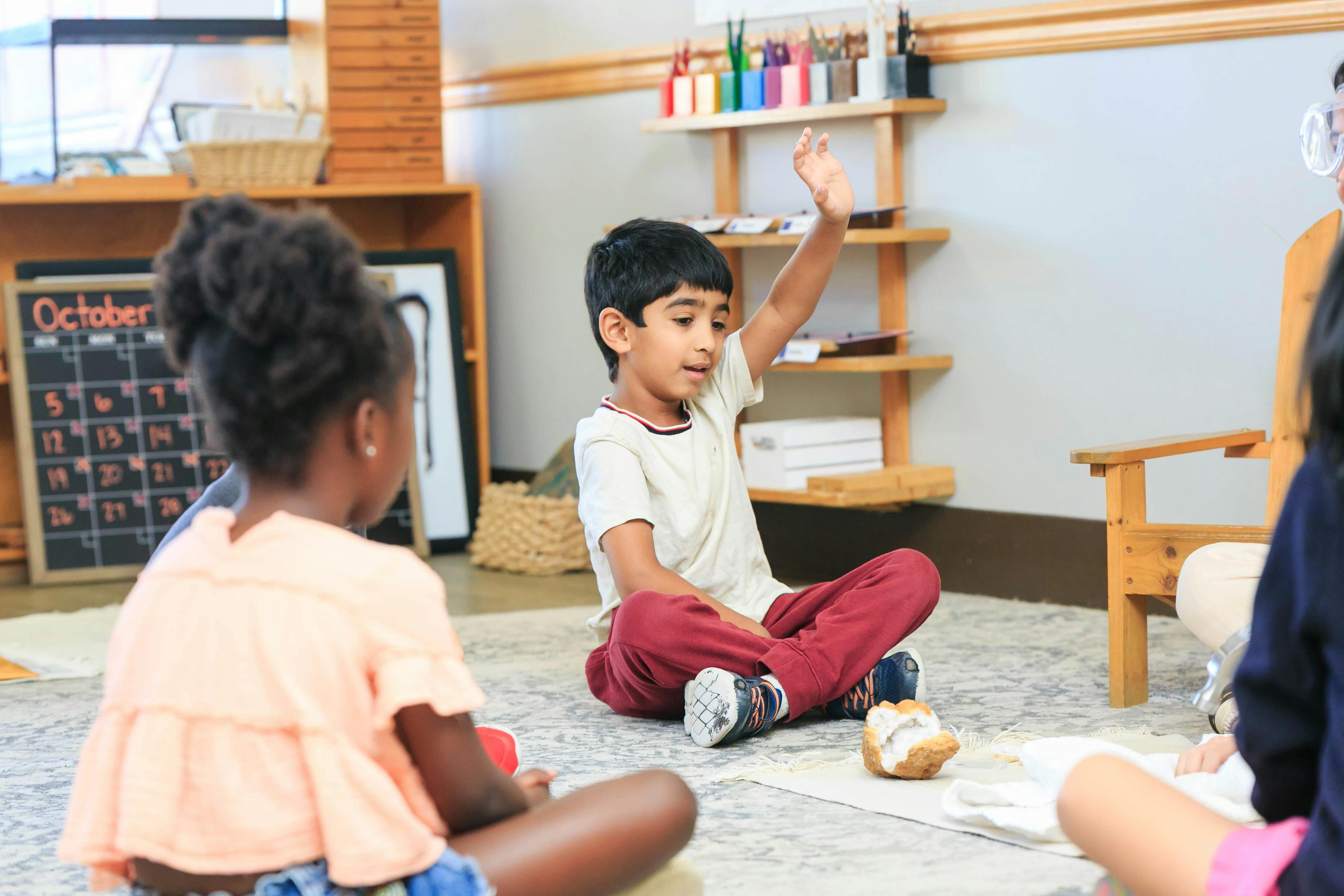 Child raising hand in a classroom with other children
