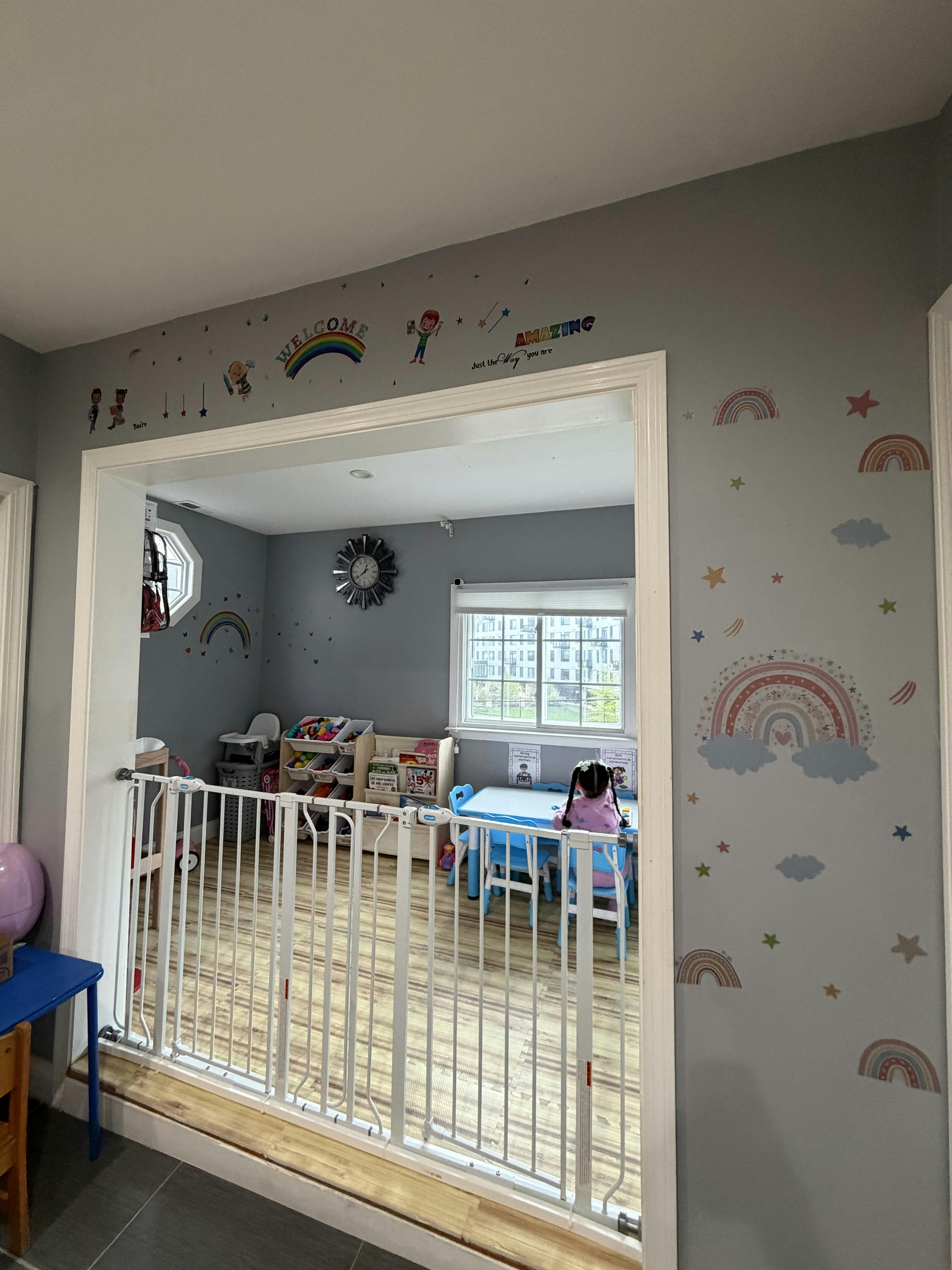child sitting at a small table in a playroom blocked by a safety gate