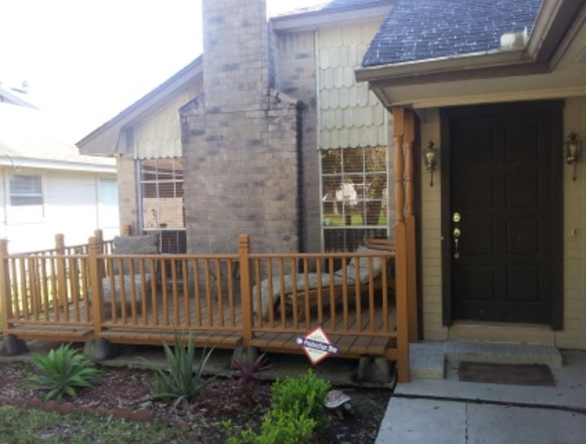 Front exterior of a house with a wooden deck and front door