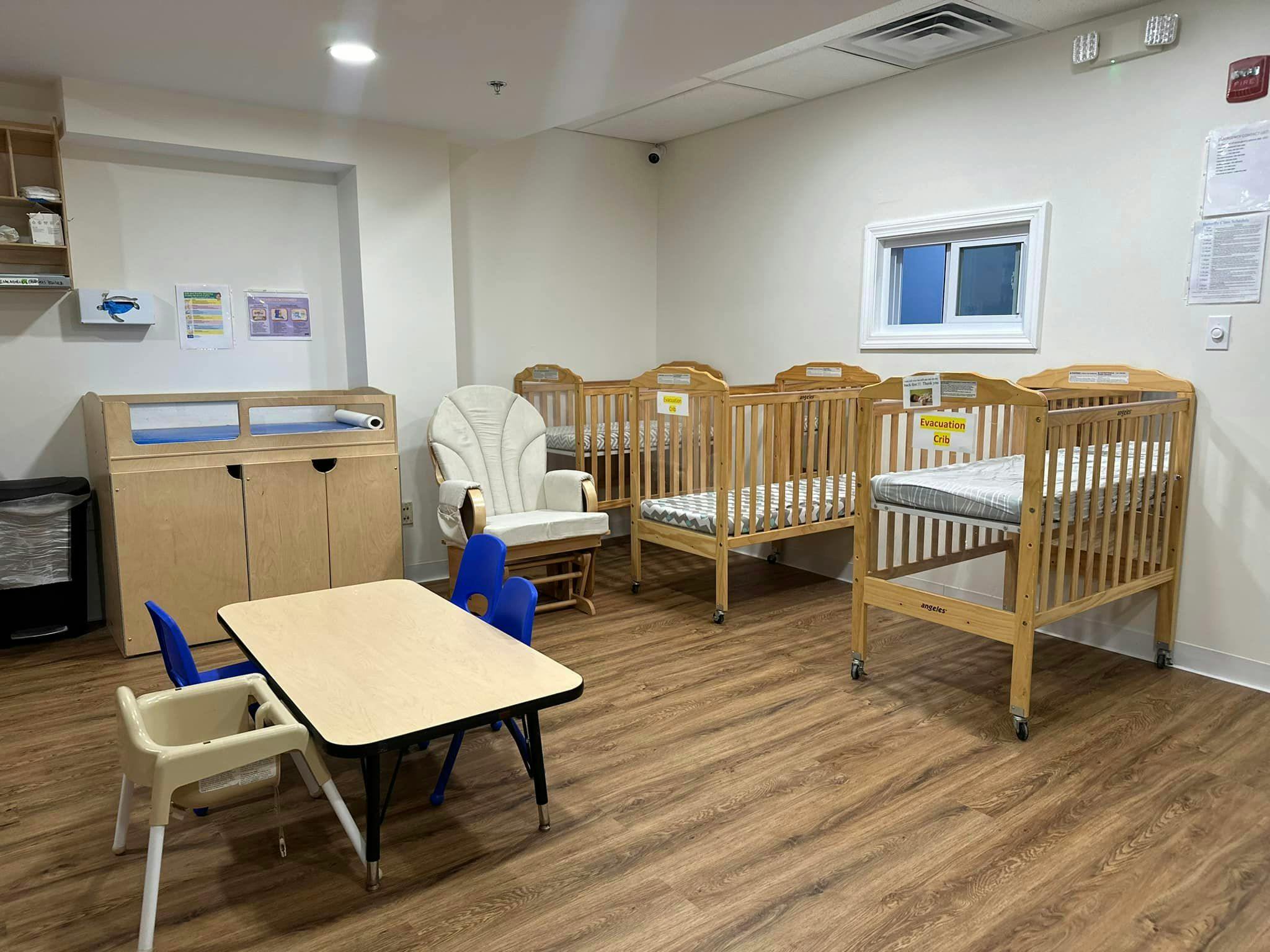 Nursery room with multiple cribs, a changing table, and a small table with chairs