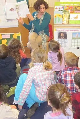 Person reading a book to a group of children in a classroom