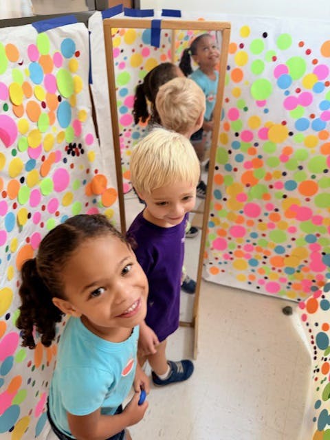 Child looking at camera, another child looking into a mirror