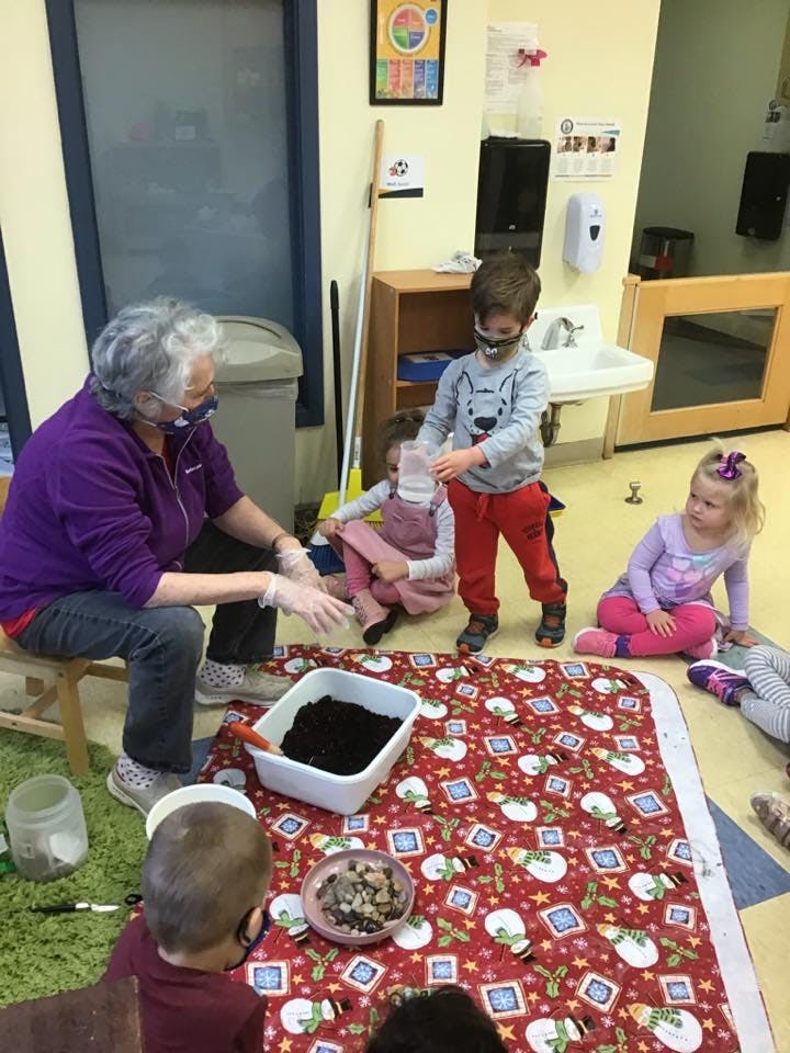 Adult and children planting in a classroom