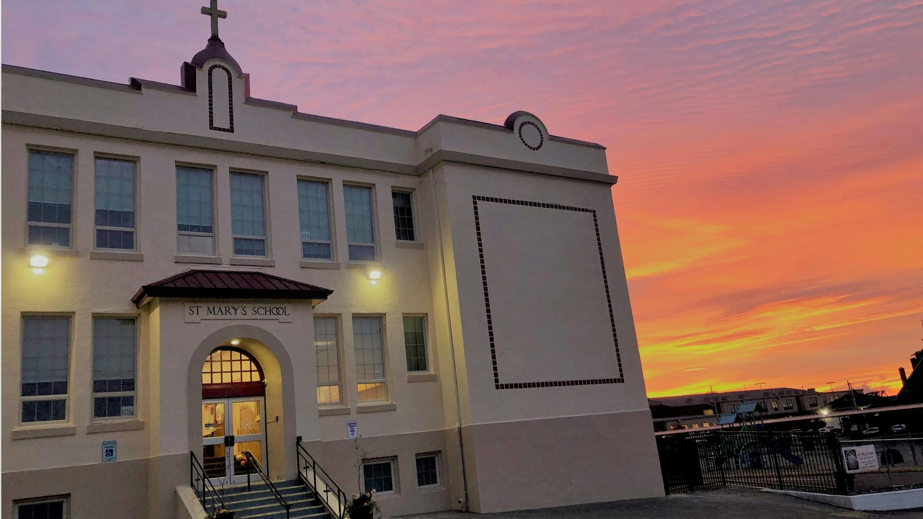 A cream-colored school building with an archway entrance and "St Mary's School" sign