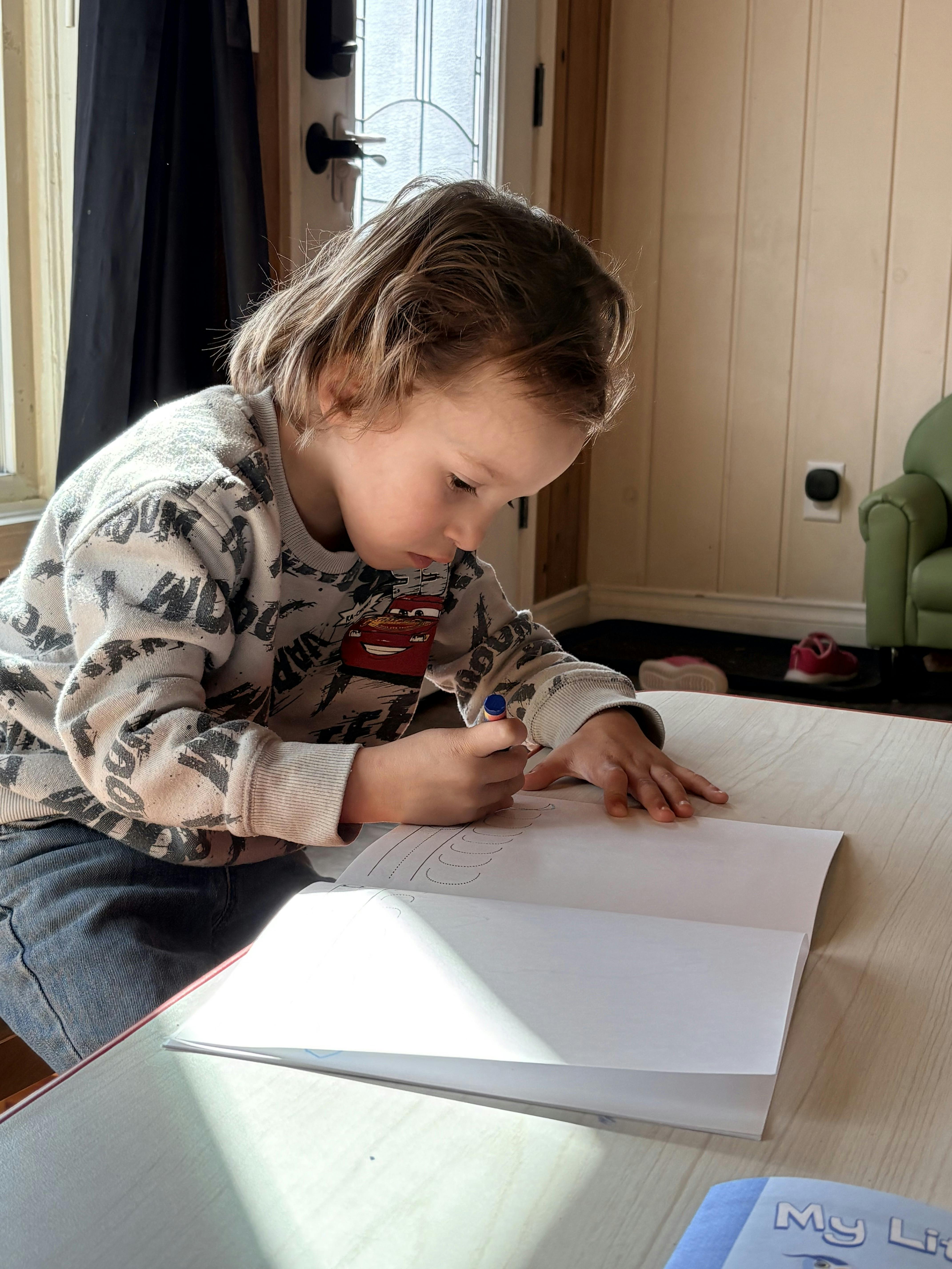 Child drawing with a blue marker in an open notebook