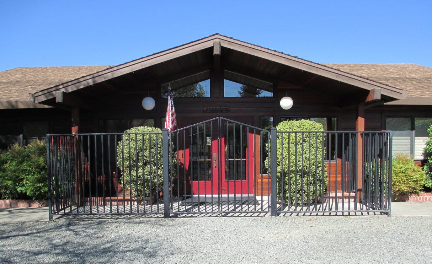 Building with red double doors behind a black metal fence