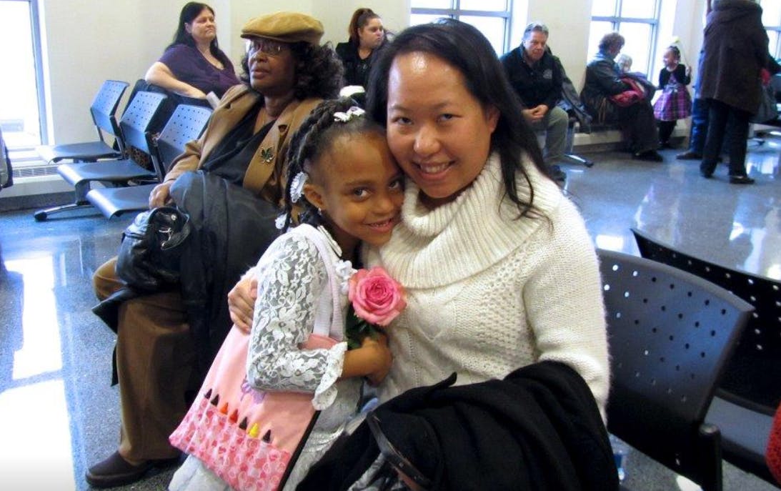 Adult and child embracing, child holding a rose