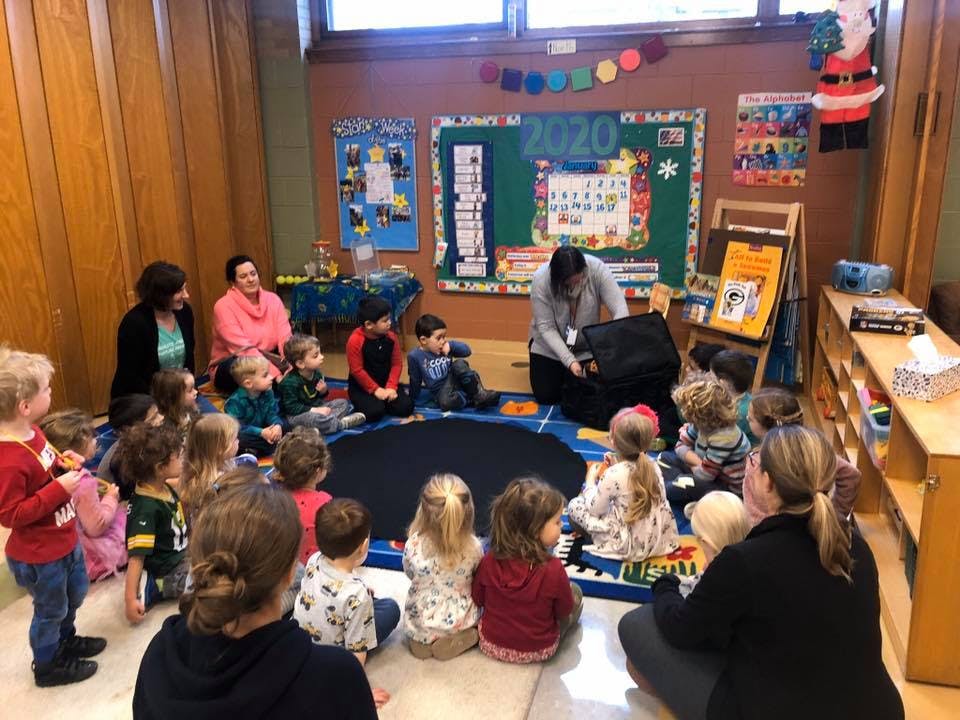 Adults and children sitting in a circle in a classroom