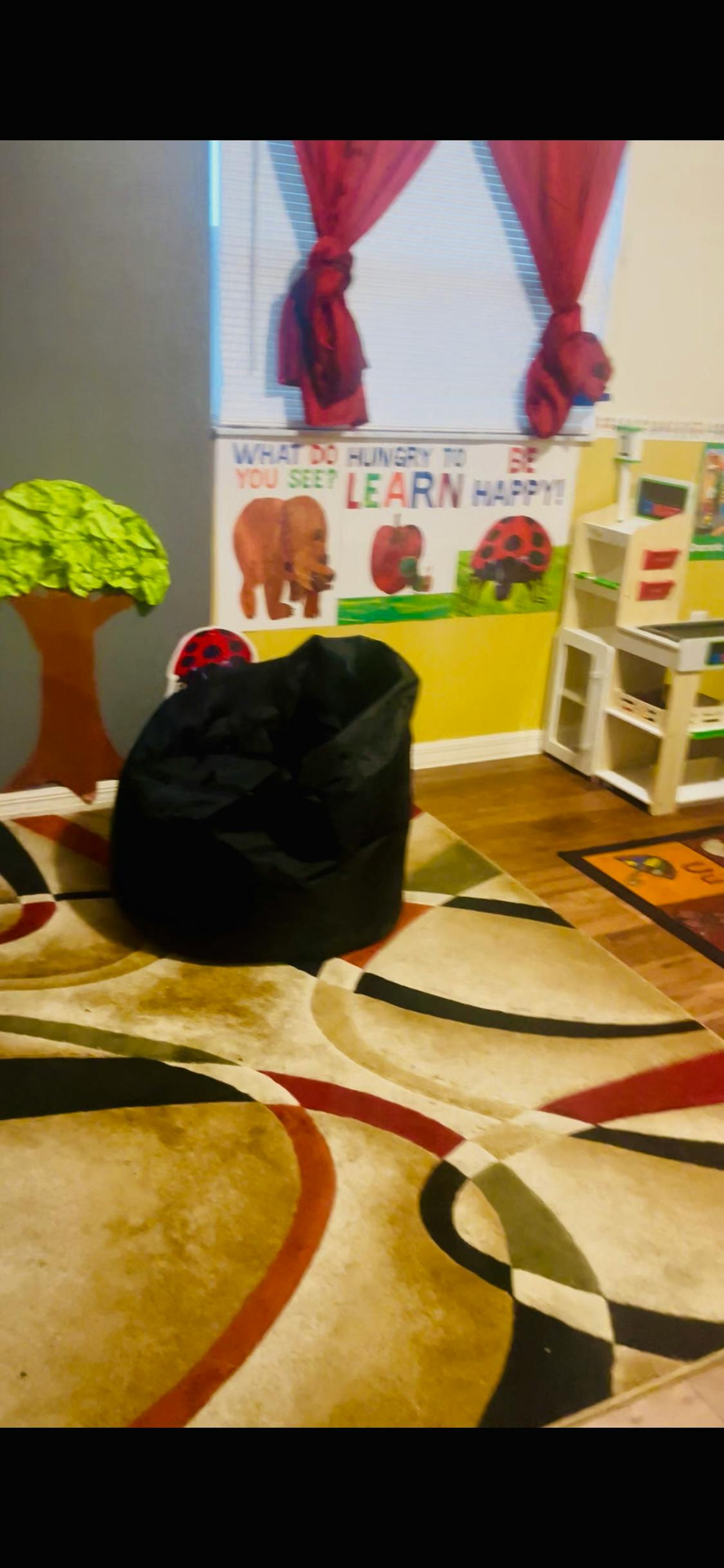 Black bean bag chair on a patterned rug in a room with a colorful wall