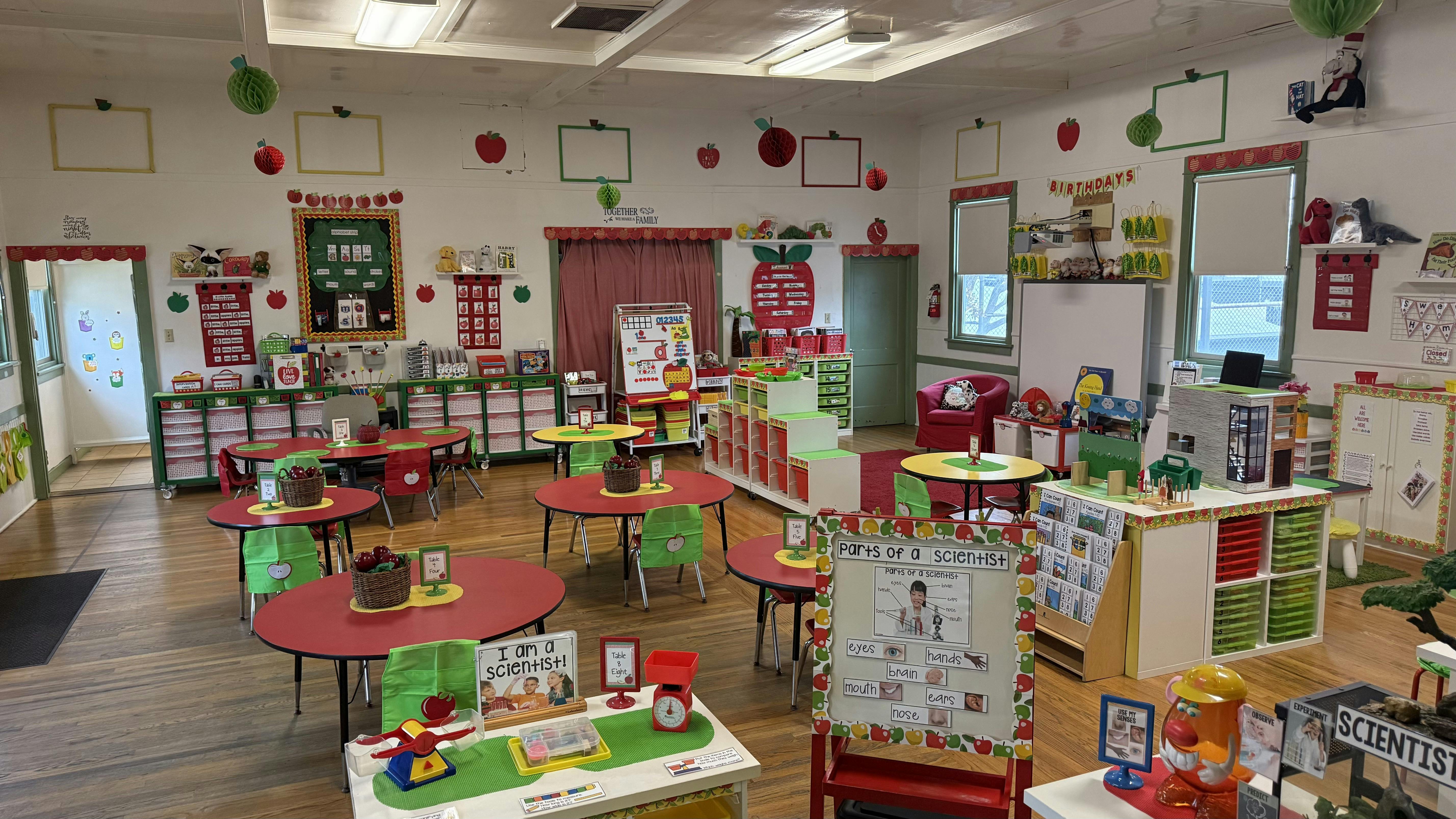 Classroom with small tables and chairs, decorated with apples
