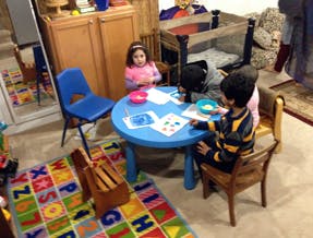 Three children sitting at a small blue table