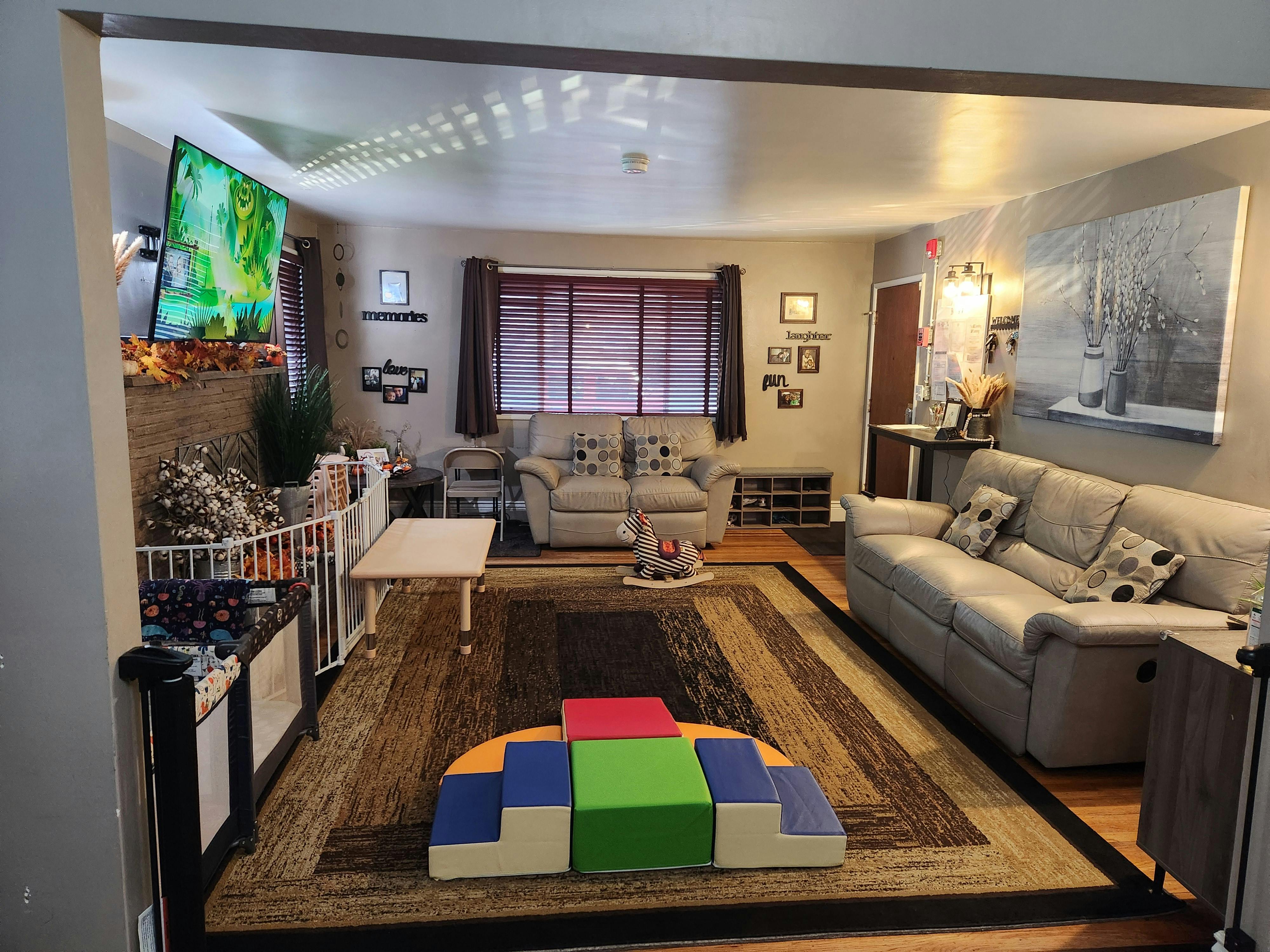 Living room with sofas, a large rug, and children's play equipment