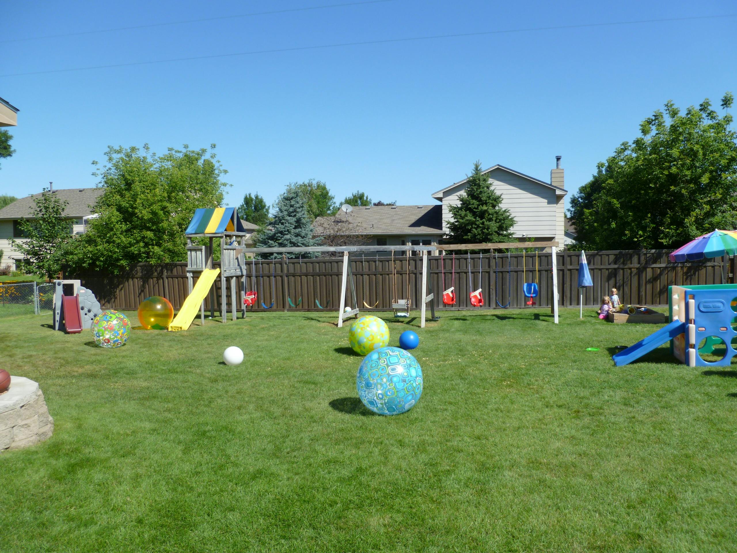 Backyard playground with swings, slides, and large inflatable balls