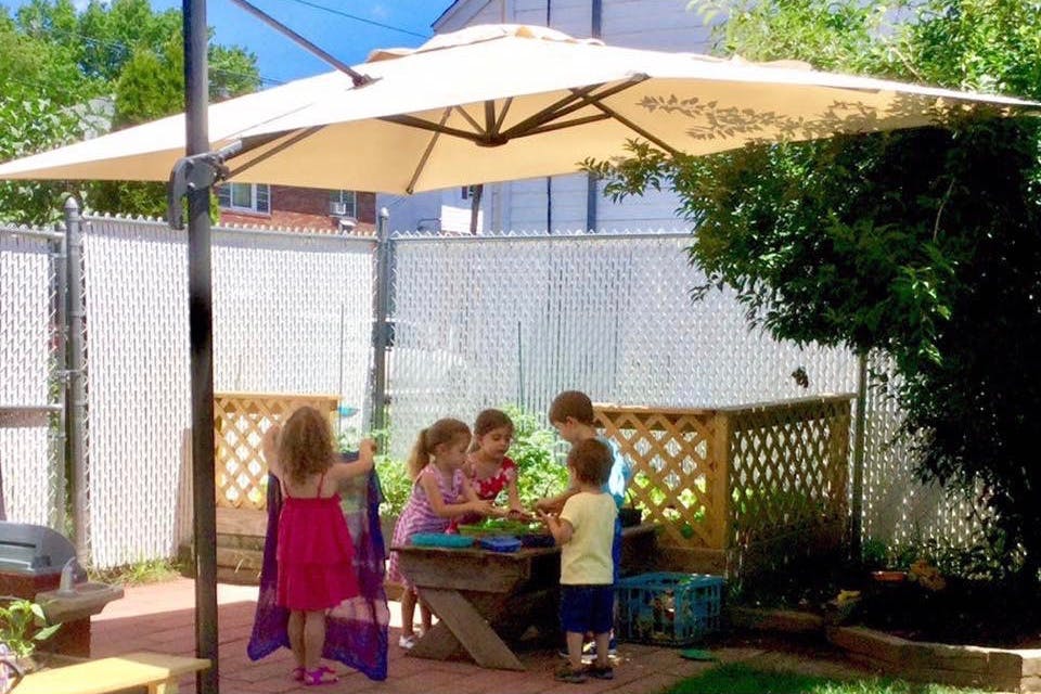 Children gathered around a table under a large patio umbrella