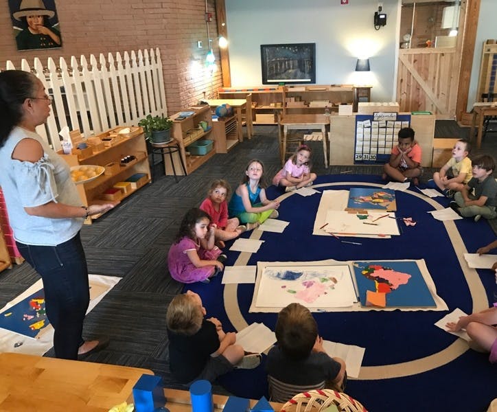 Adult standing in front of children sitting on a rug in a classroom