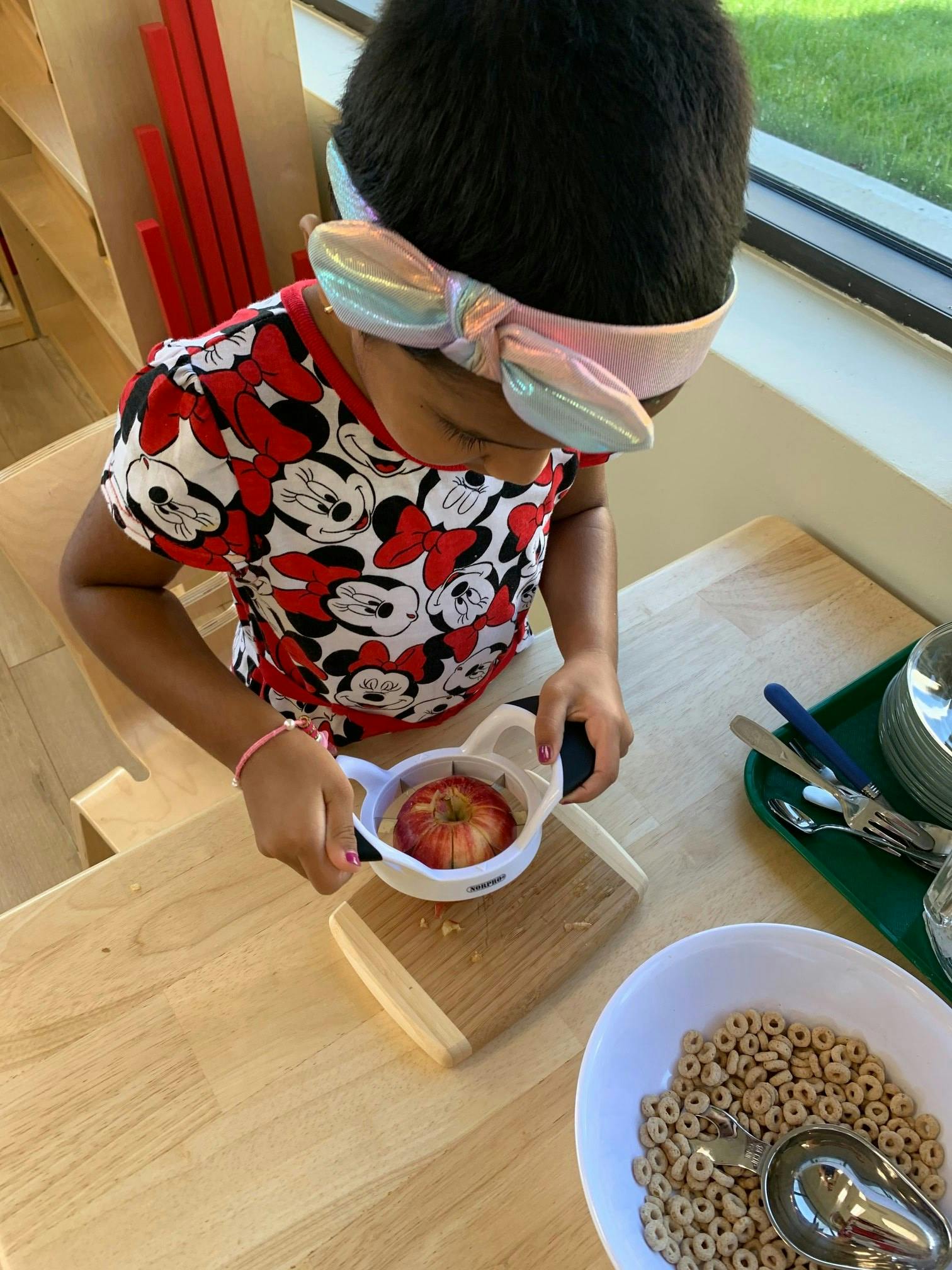 Child using an apple slicer on a cutting board