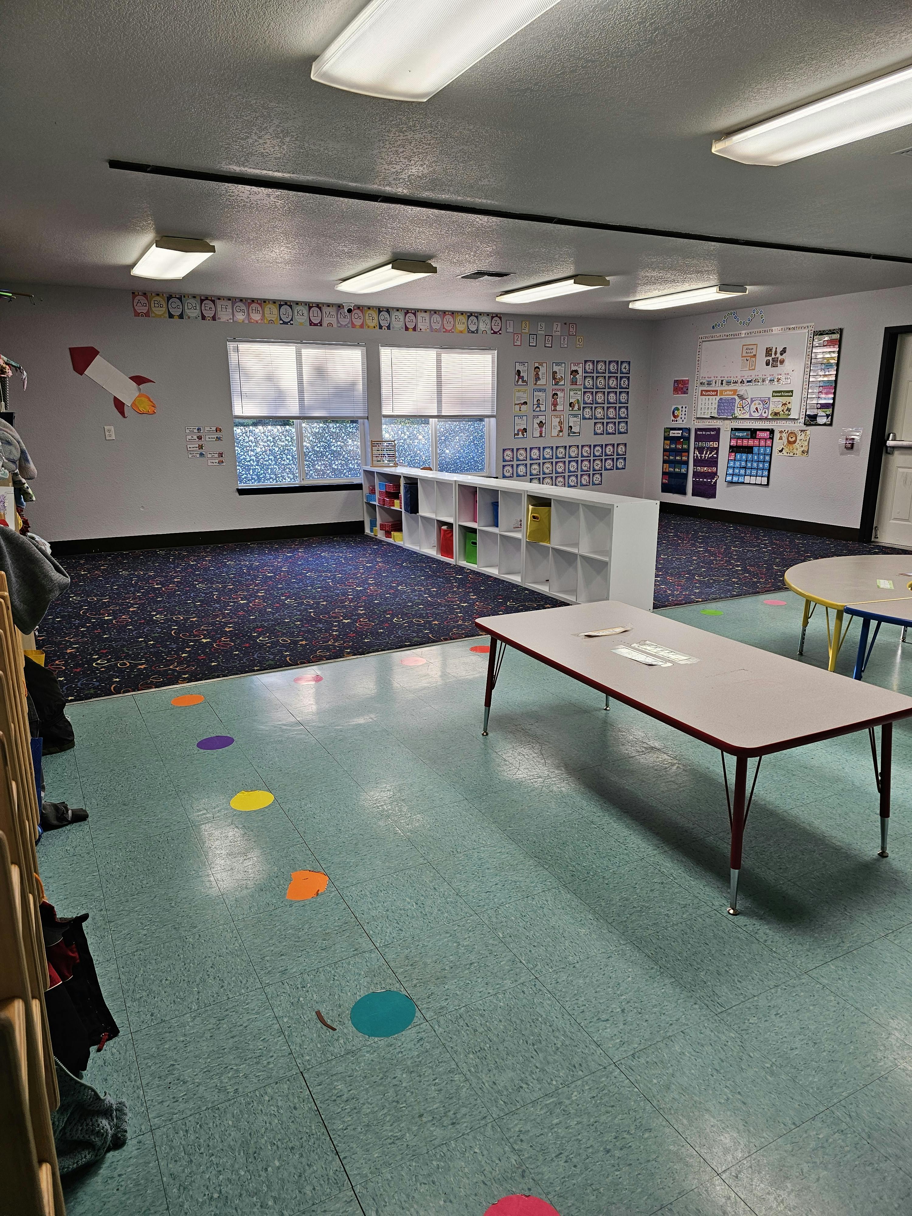 Empty classroom with tables, shelves, and colorful floor dots