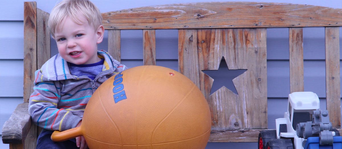 Child sitting on a large orange bouncy ball