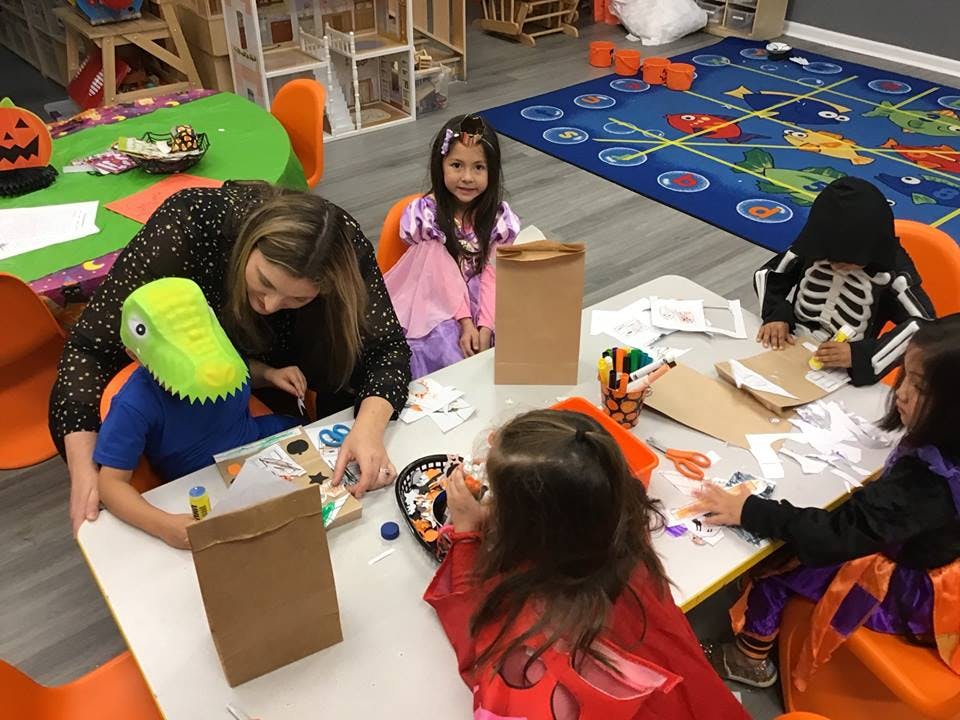 Adult and children in costumes doing crafts at a table