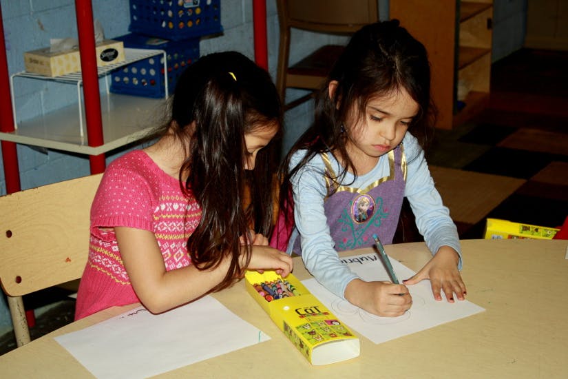 Two children drawing at a table