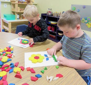 Two children playing with colorful blocks at a table