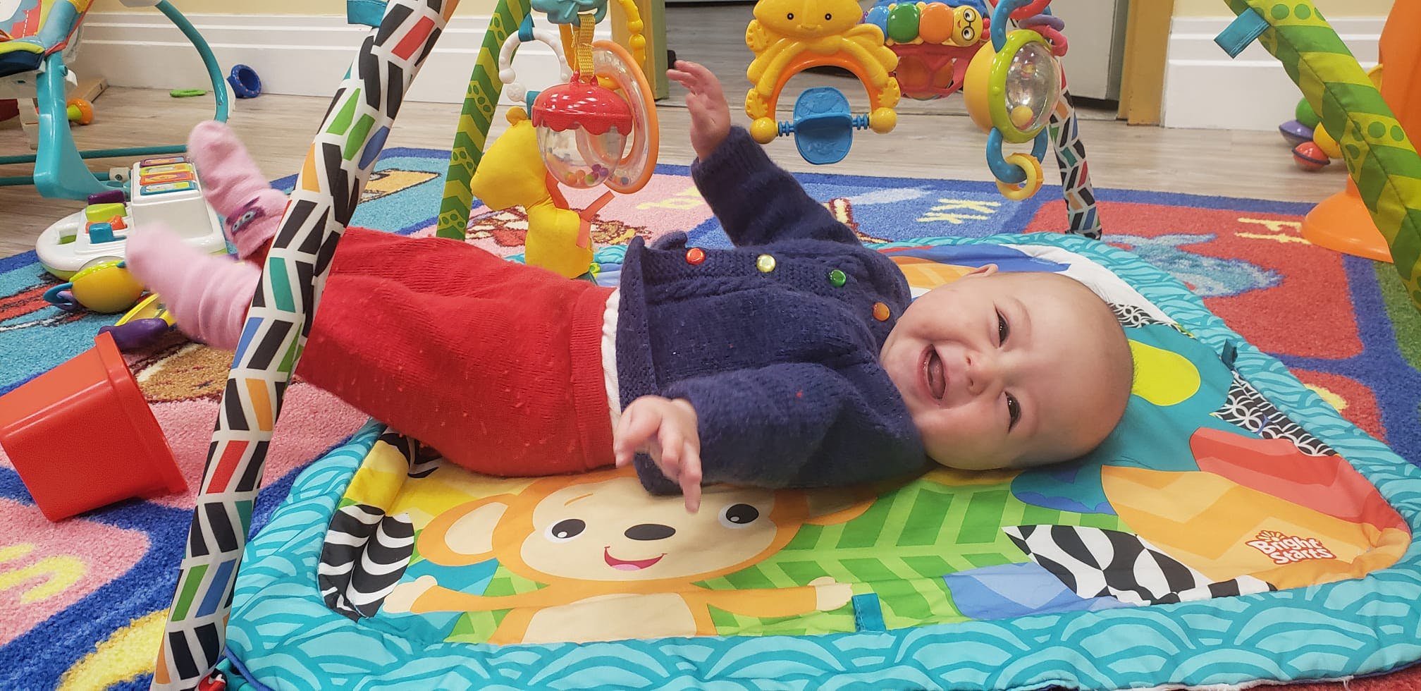 Child lying on a playmat under an activity arch