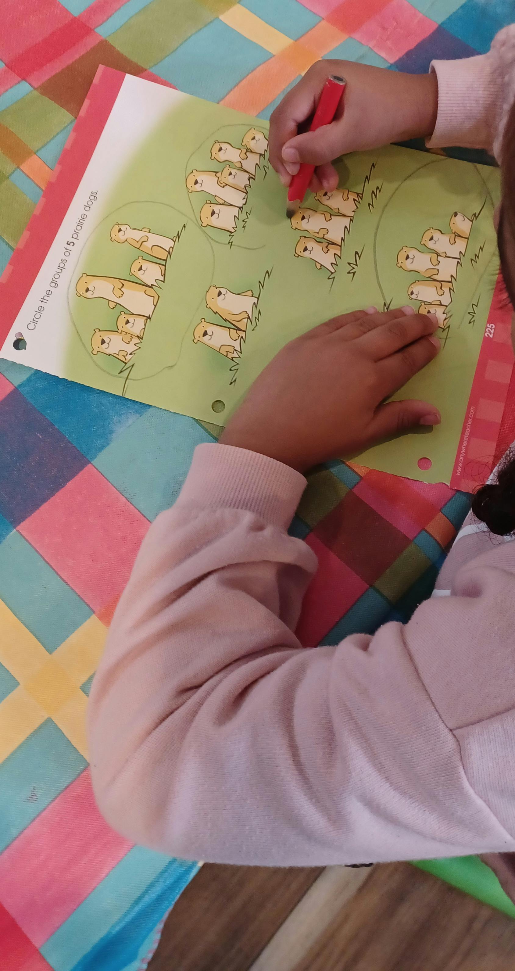 Child's hands coloring a worksheet with cartoon animals