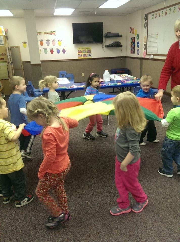 Children playing with a colorful parachute in a classroom