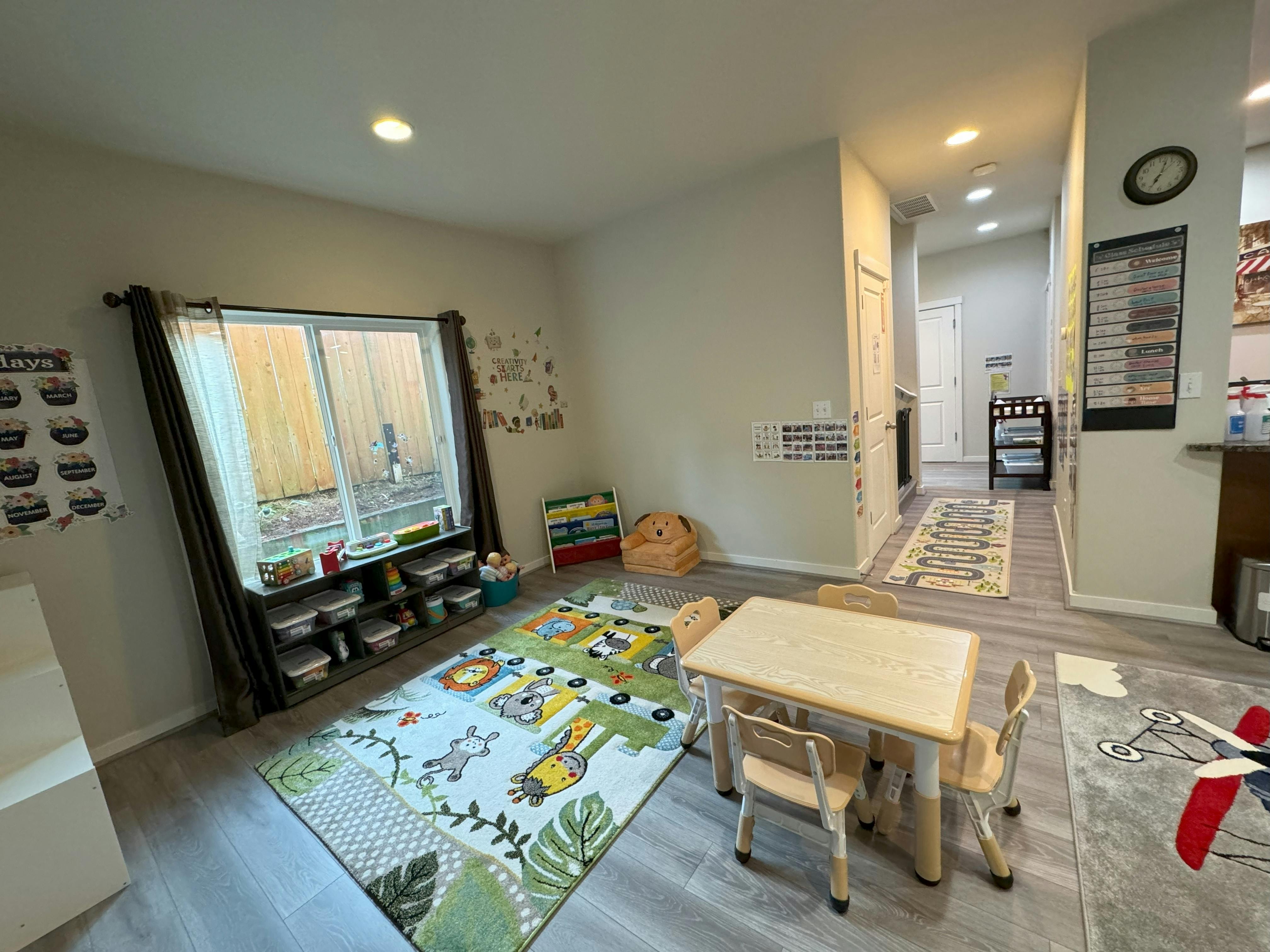 Playroom with a small table and chairs, a colorful rug, and a window