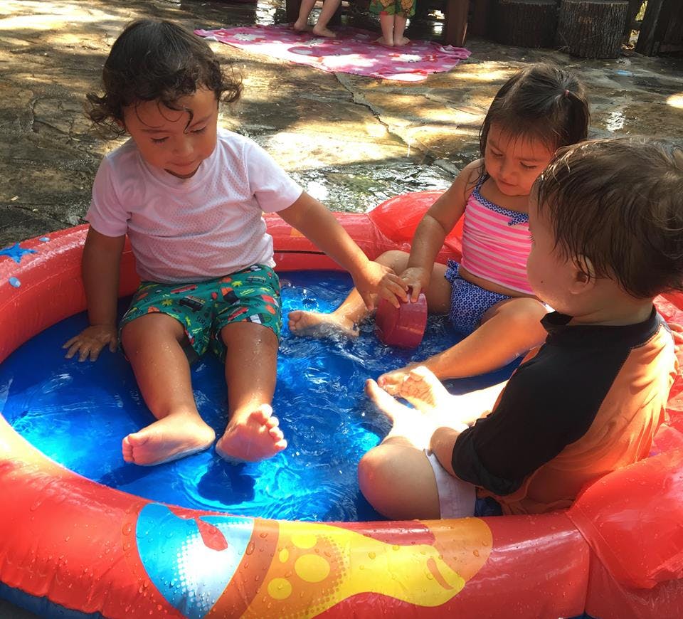 Three children playing in a small inflatable pool