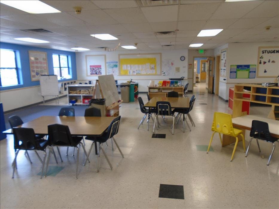Classroom with multiple tables and chairs, whiteboards, and learning materials