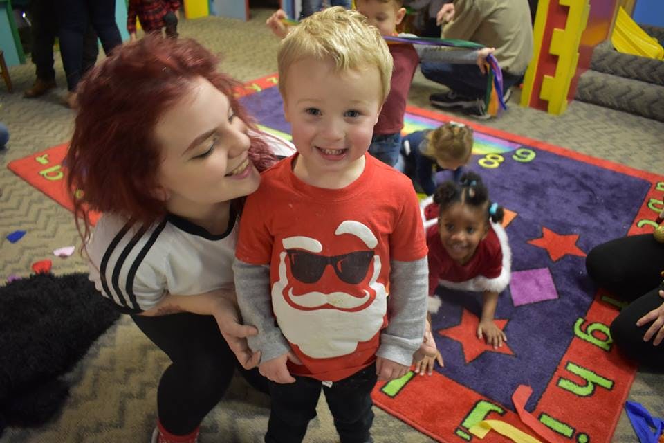 Person with red hair smiling at a child in a red shirt