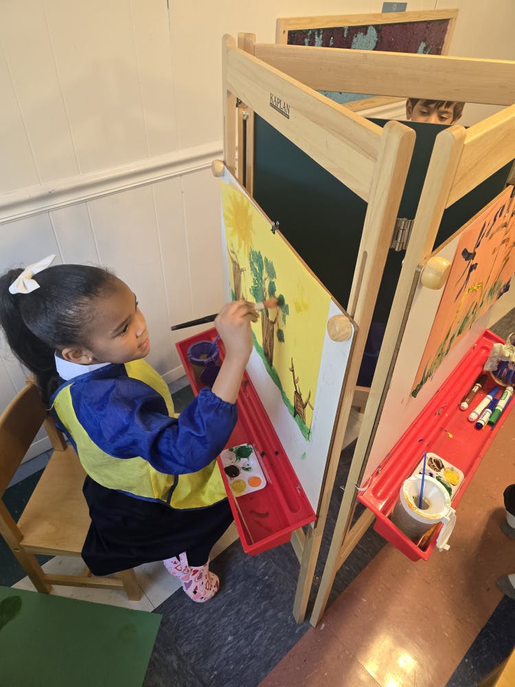 Child painting at an easel with yellow paper