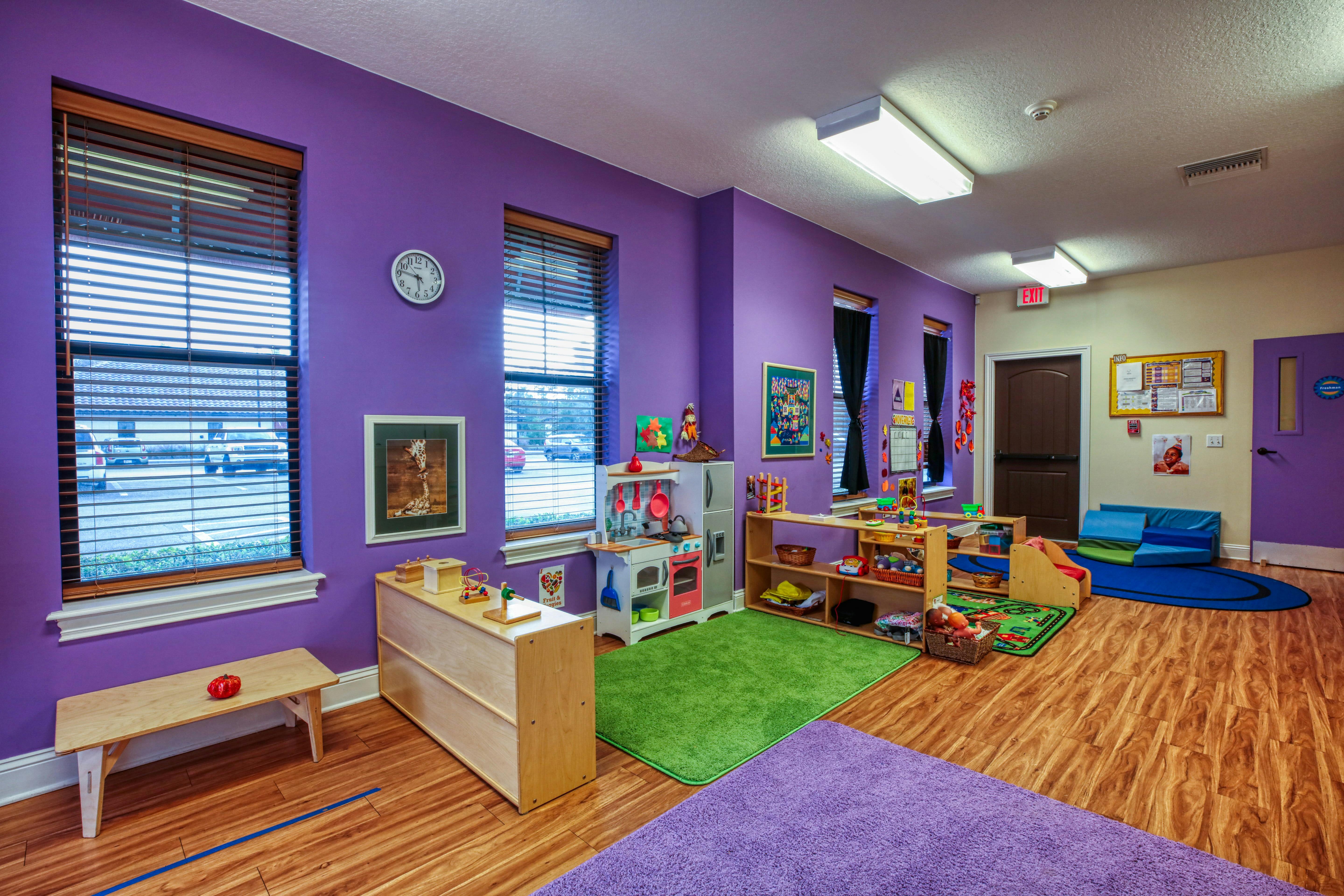 Playroom with purple walls, windows, toy kitchen, and storage shelves