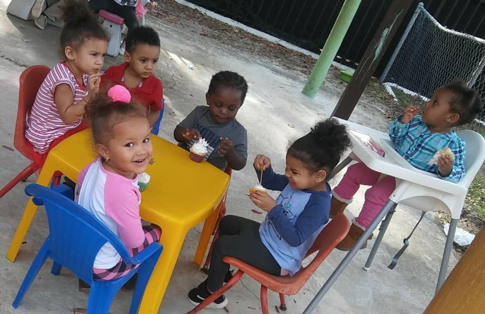 Six children sitting around a small yellow table