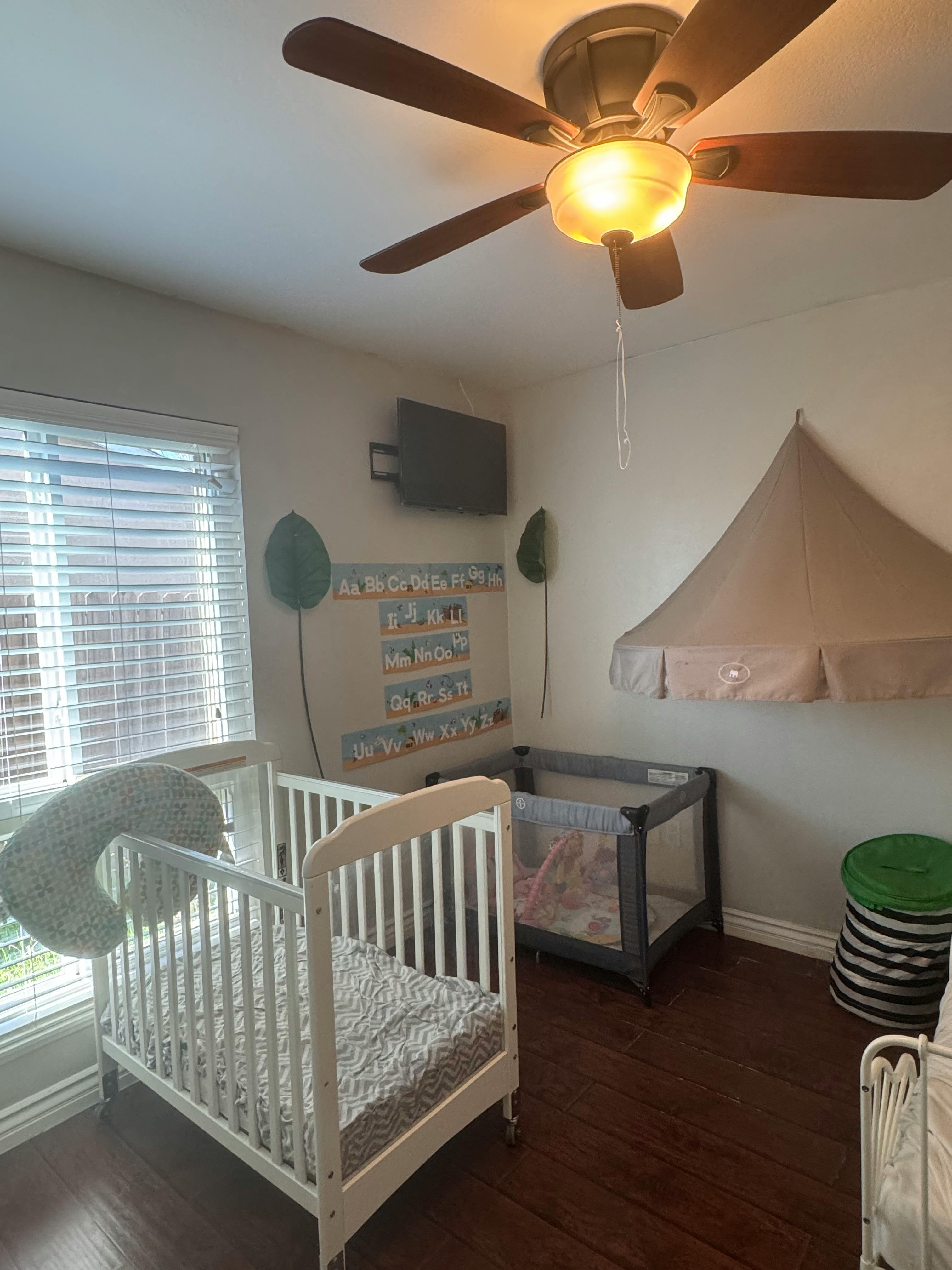 Crib and playpen in a room with an alphabet chart