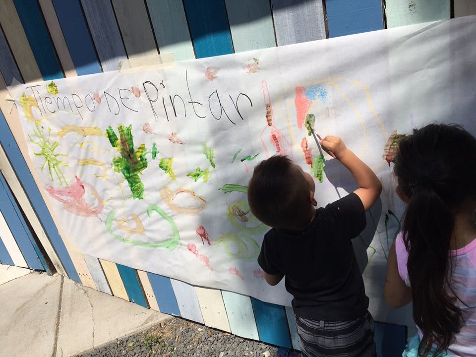 Two children painting on a large white banner