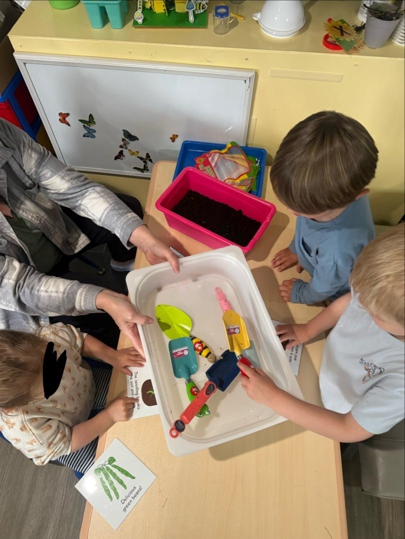 People and children playing with gardening tools in trays of soil and water