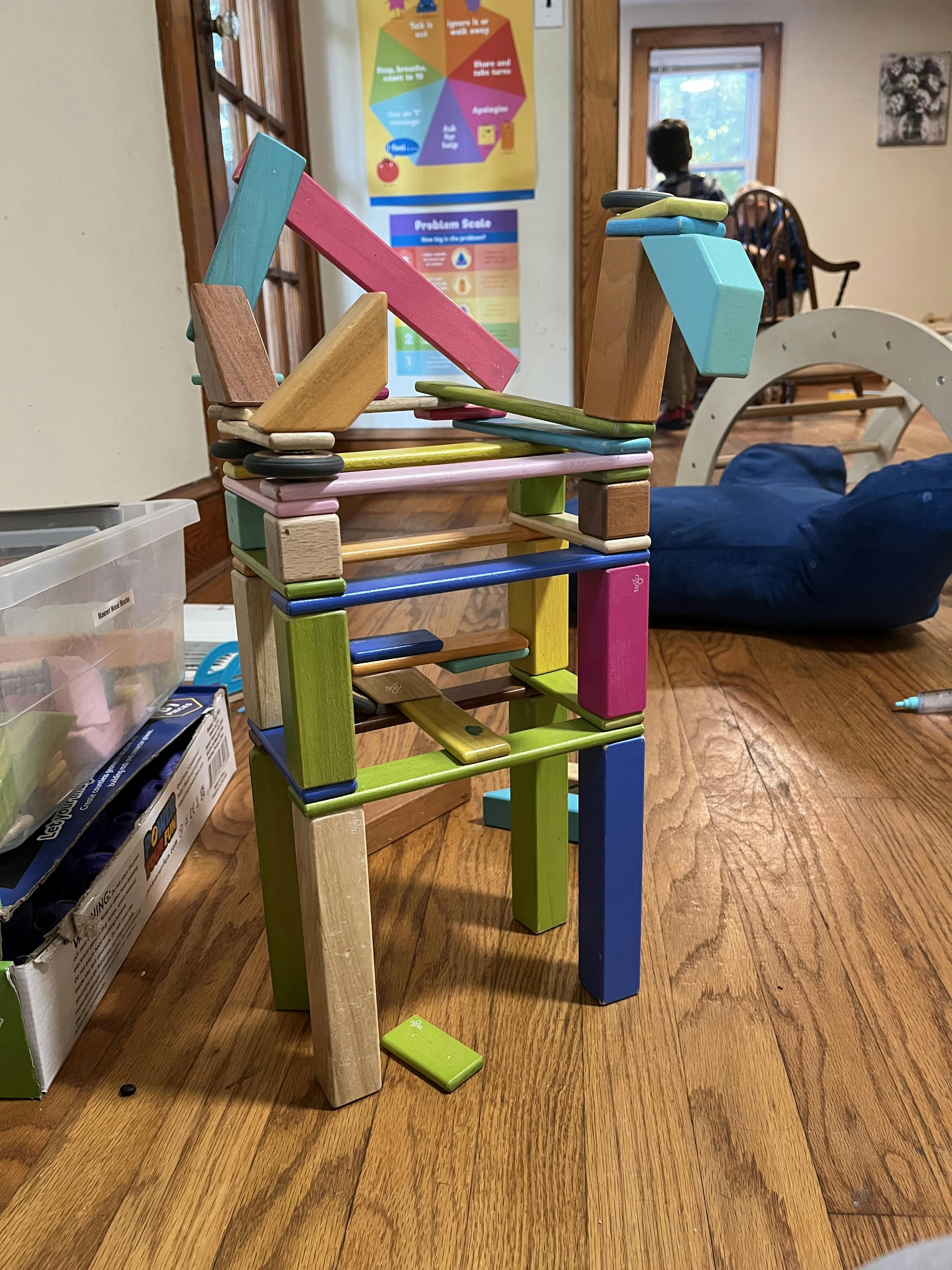 Tall structure built from colorful wooden blocks on a wooden floor